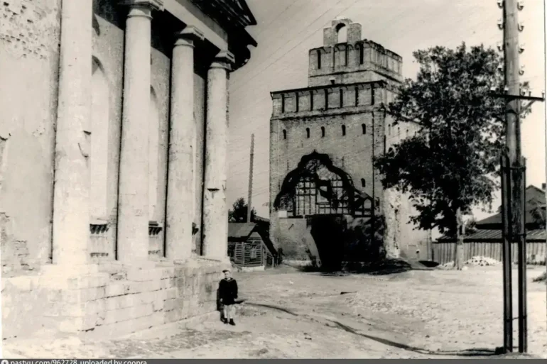 Коломна, ул. Лазарева, Крестовоздвиженская церковь и Пятницкие ворота, 1956 года. Также виден телеграфный столб и деревянный дом, отраженный на гравюре И. Н. Павлова в 1920-е гг. Автор фото: Кузнецов Д. Д. Фото с сайта pastvu.com. Подпись на вотермарке: uploaded by coopra.
