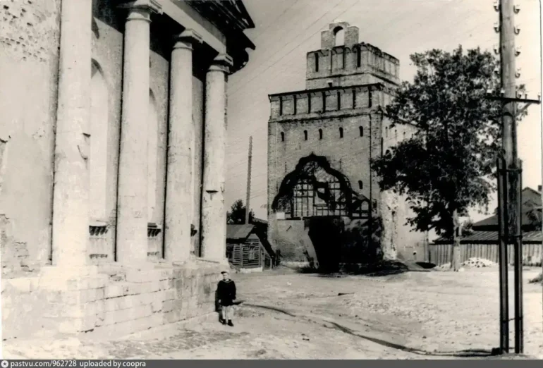Коломна, ул. Лазарева, Крестовоздвиженская церковь и Пятницкие ворота, 1956 года. Также виден телеграфный столб и деревянный дом, отраженный на гравюре И. Н. Павлова в 1920-е гг. Автор фото: Кузнецов Д. Д. Фото с сайта pastvu.com. Подпись на вотермарке: uploaded by coopra.